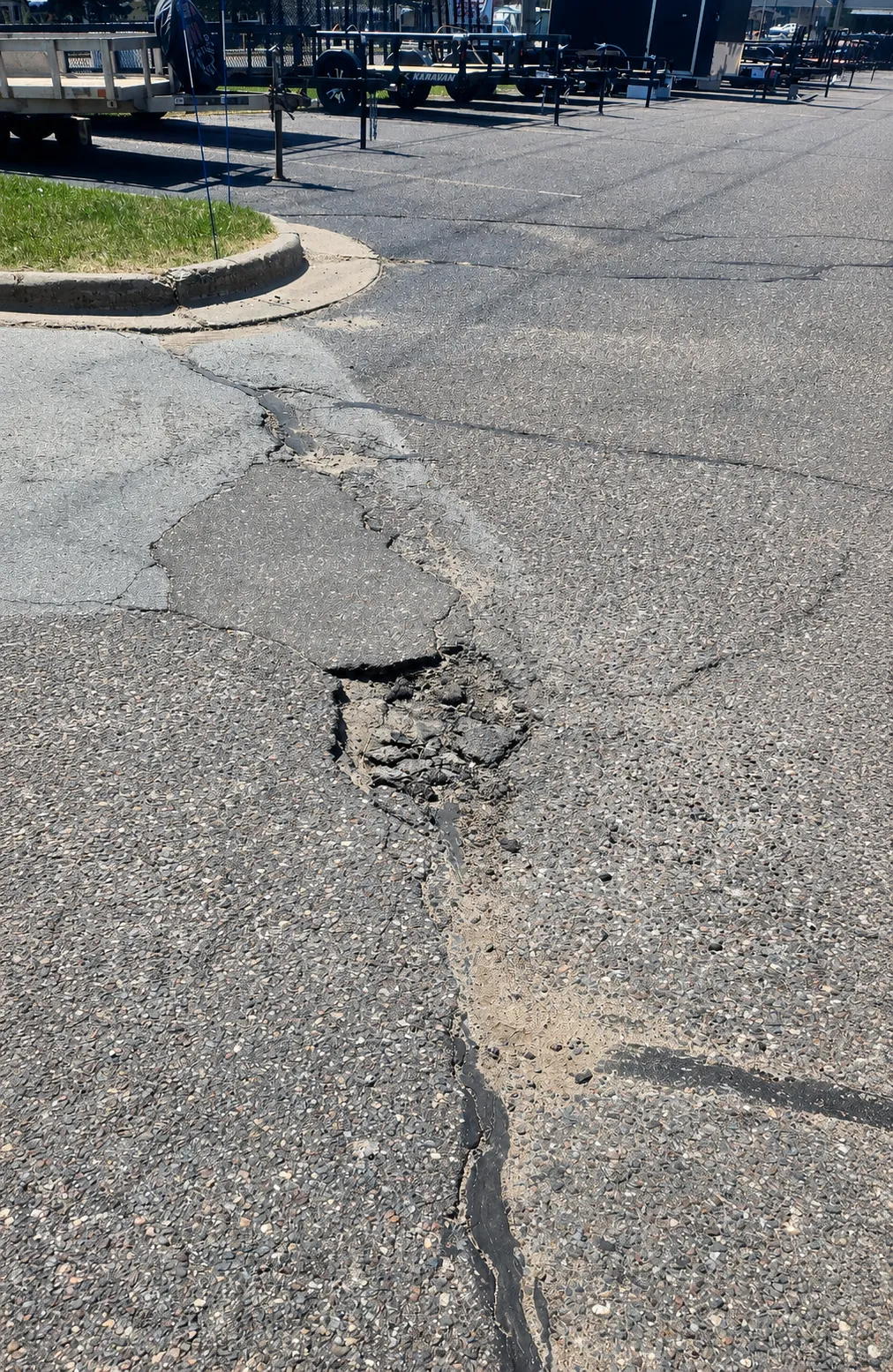 Deteriorated asphalt pavement with wide cracks, failed edges, and previous crack repairs