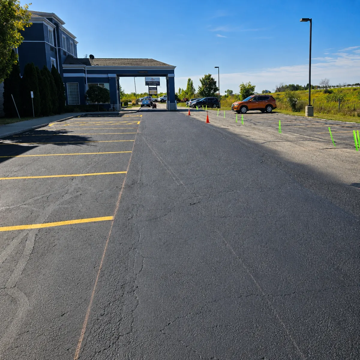 Commercial parking lot with freshly sealcoated asphalt beside untreated pavement.