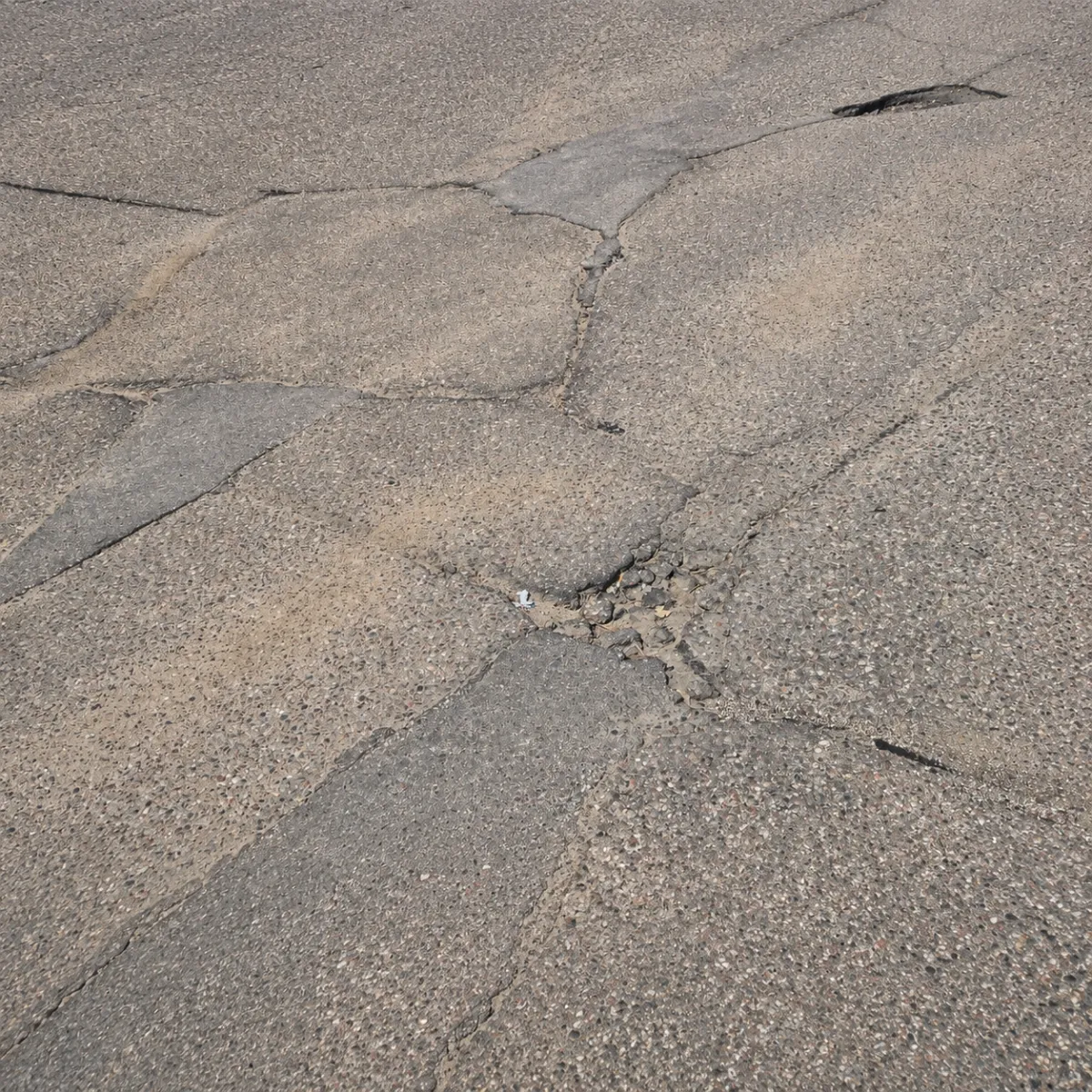 Deteriorated asphalt pavement with interconnected cracks and localized surface failure.