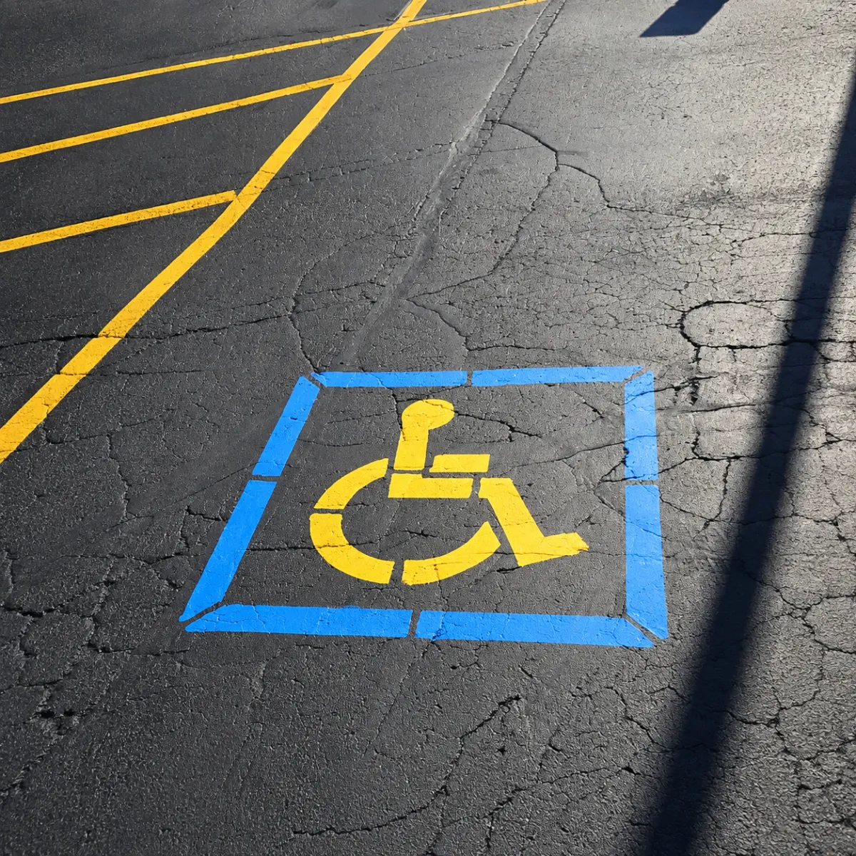 Fresh yellow ADA parking markings and numbered parking spaces on a paved parking lot.