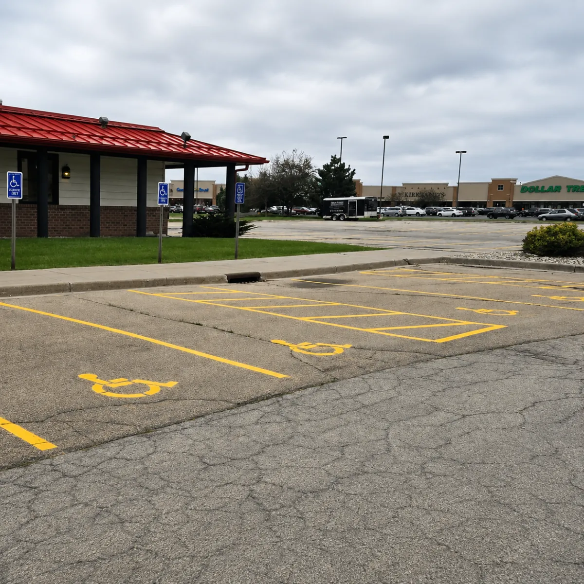 Accessible parking spaces with yellow ADA wheelchair symbols and striped access aisles in a commercial parking lot