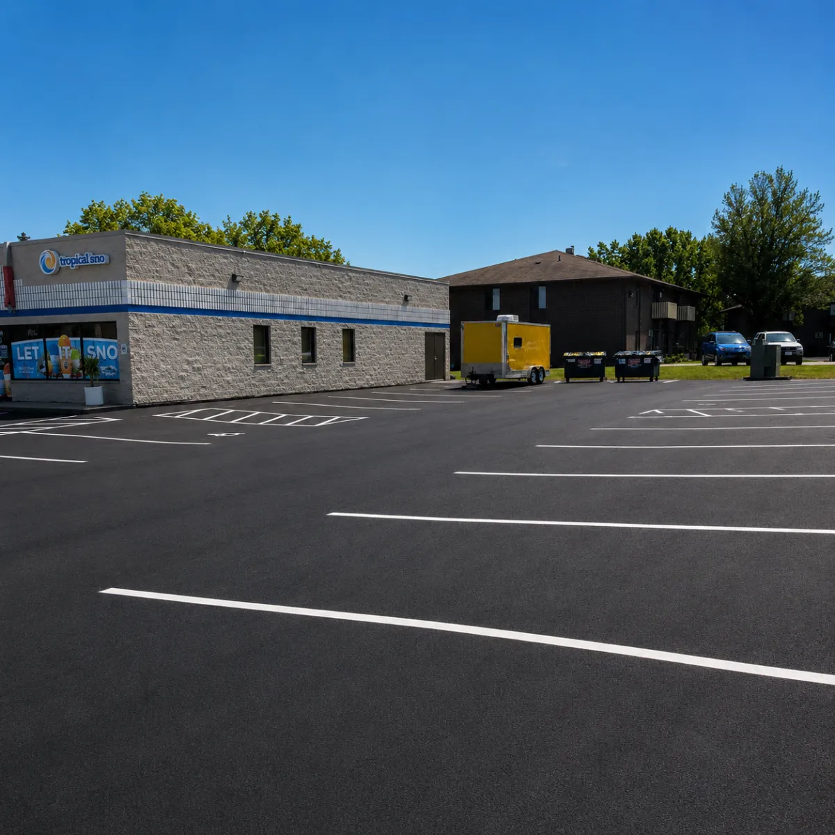 Freshly sealcoated commercial parking lot with bright white parking stall striping beside a business