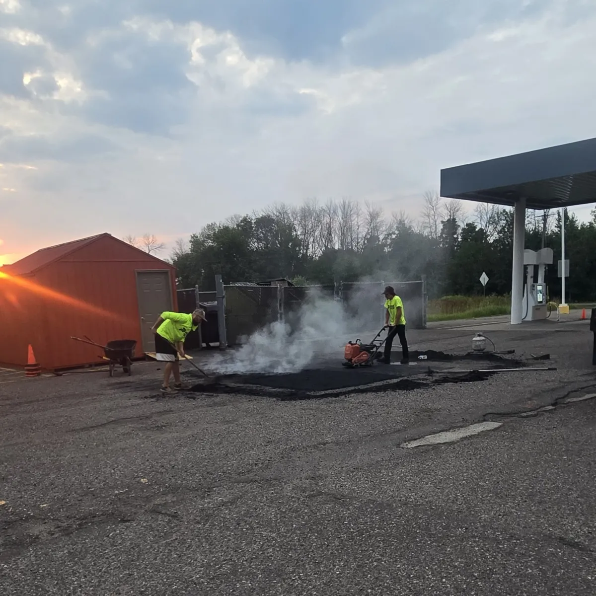 Crew performing commercial asphalt patching and pavement repair near a fueling area in Wisconsin