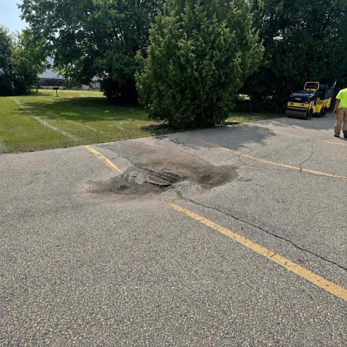 Standing water and deteriorated asphalt around a catch basin in a Wisconsin parking lot