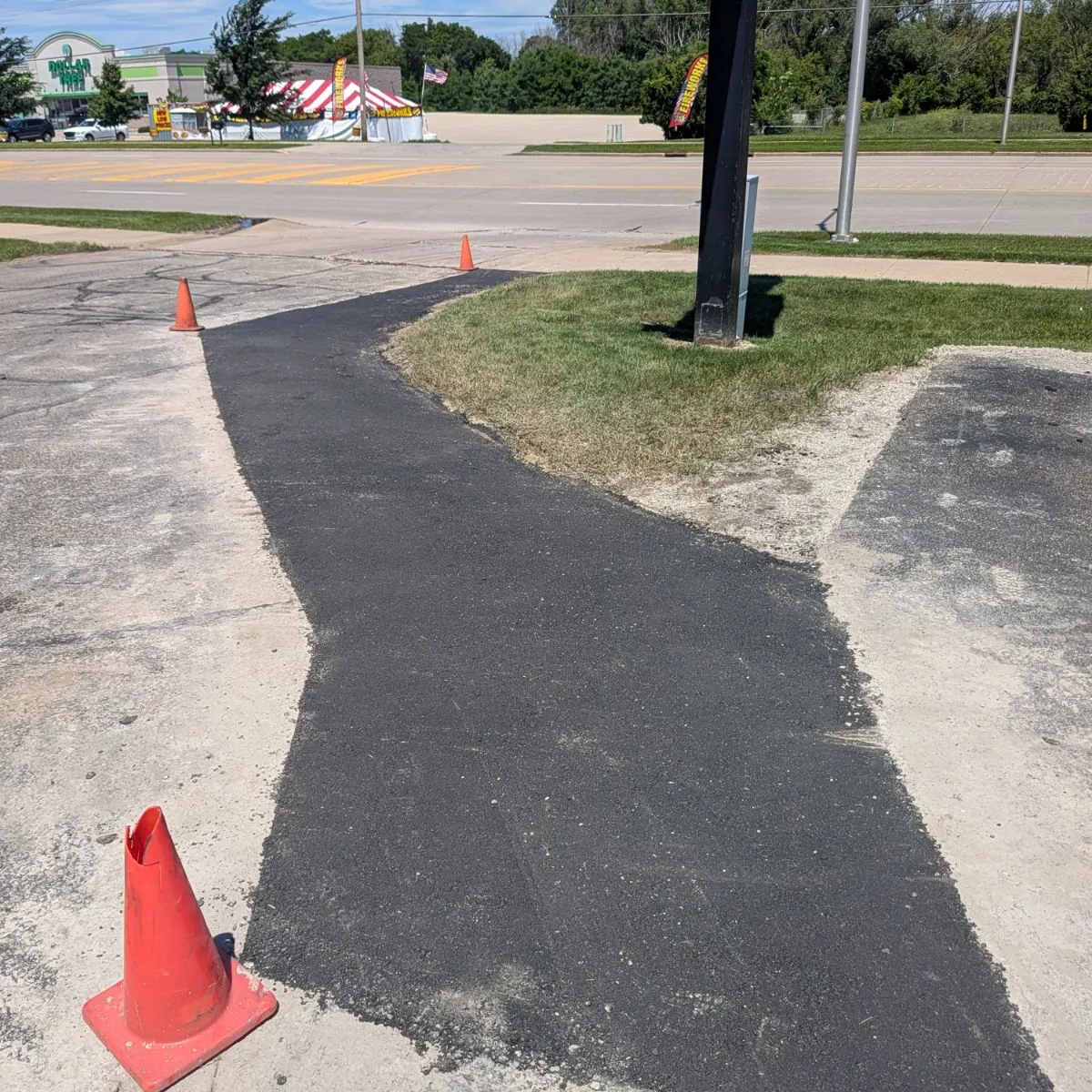 Fresh asphalt utility cut repair restoring pavement around a commercial entrance in Wisconsin