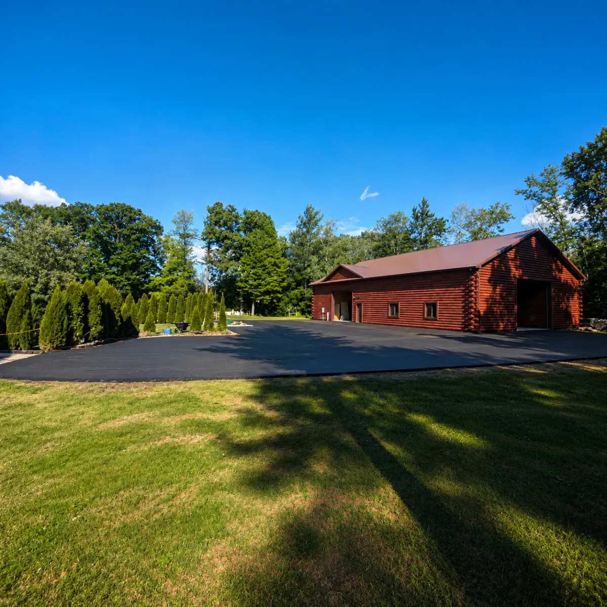 Newly paved residential asphalt driveway and parking area beside a large detached garage.
