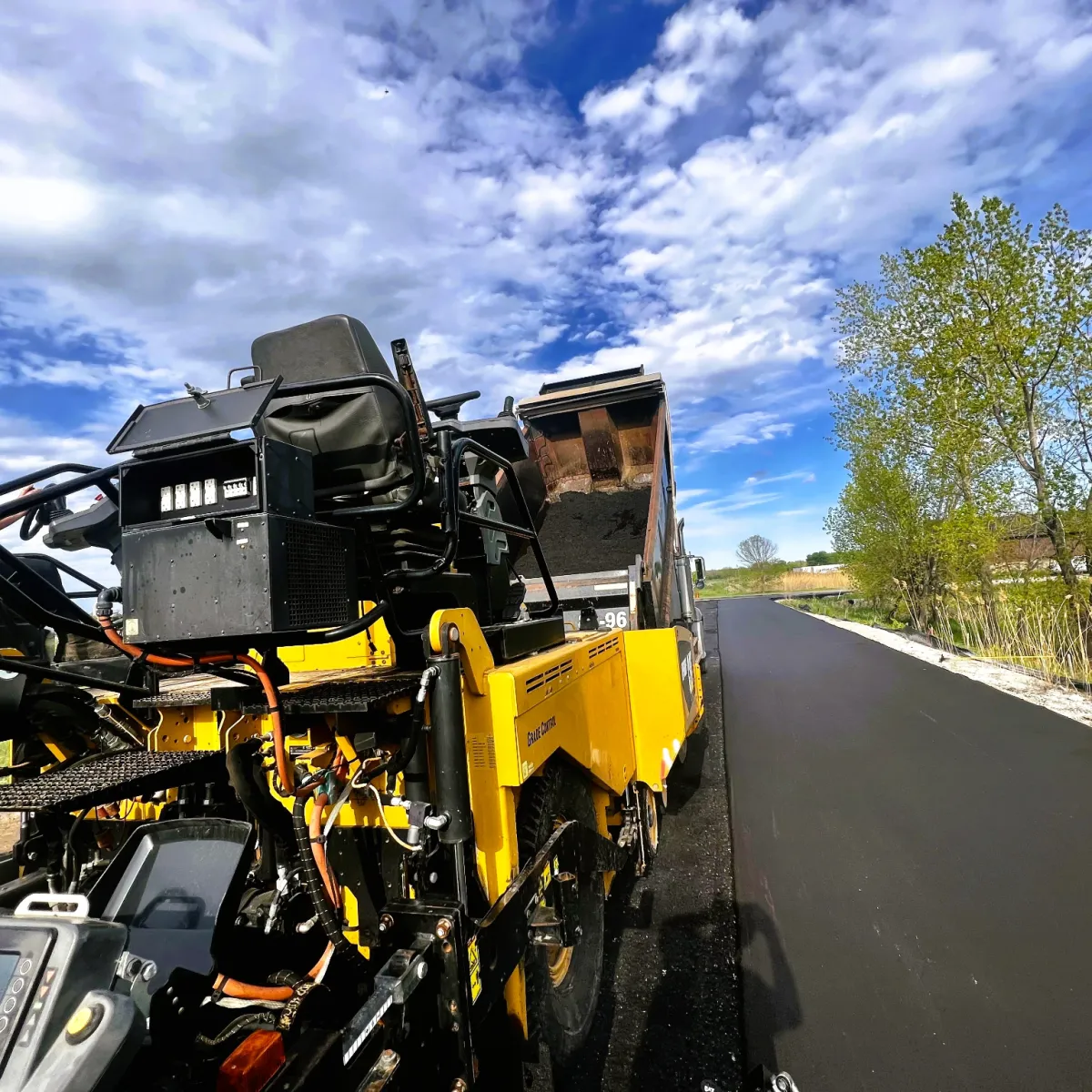 Asphalt paving machine placing fresh hot mix pavement on a newly constructed roadway.