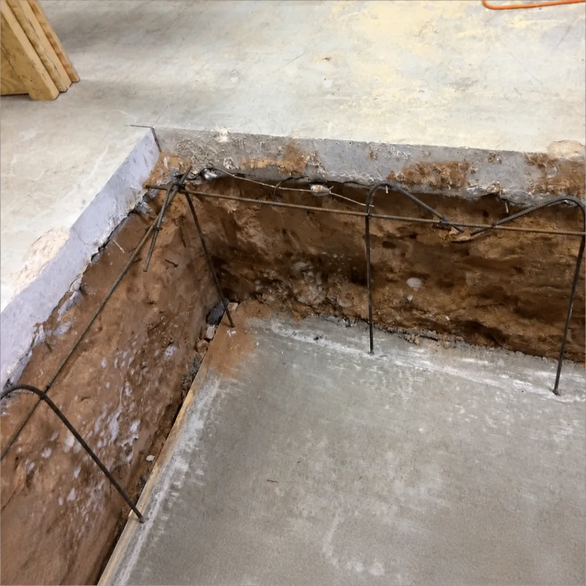 Concrete slab section removed to expose soil and reinforcing steel for concrete repair and replacement.