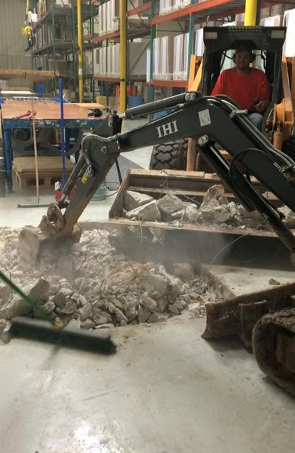 Crew using compact equipment to remove and clear demolished concrete inside a commercial warehouse