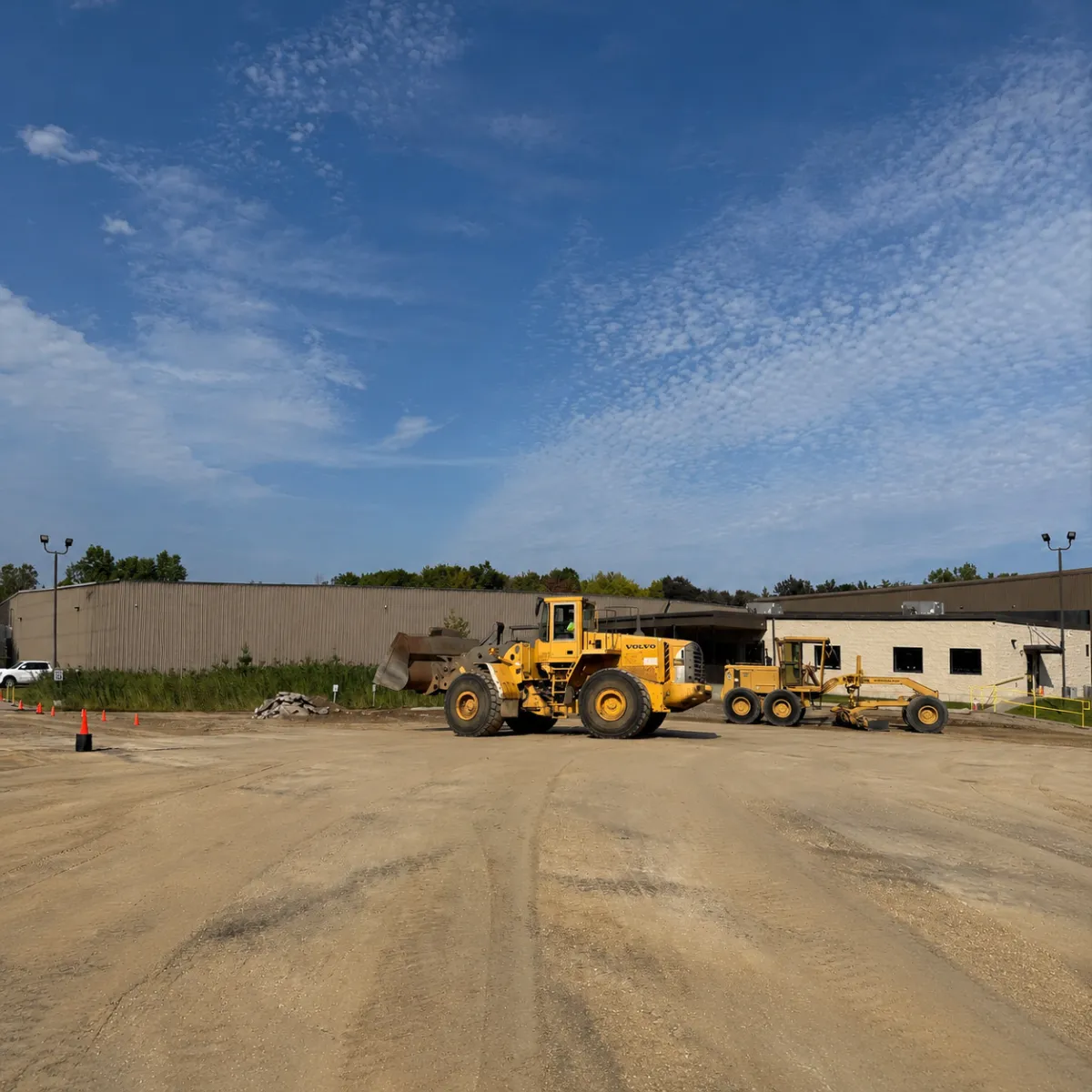 Heavy equipment grading and preparing the base for a large commercial pavement construction project.