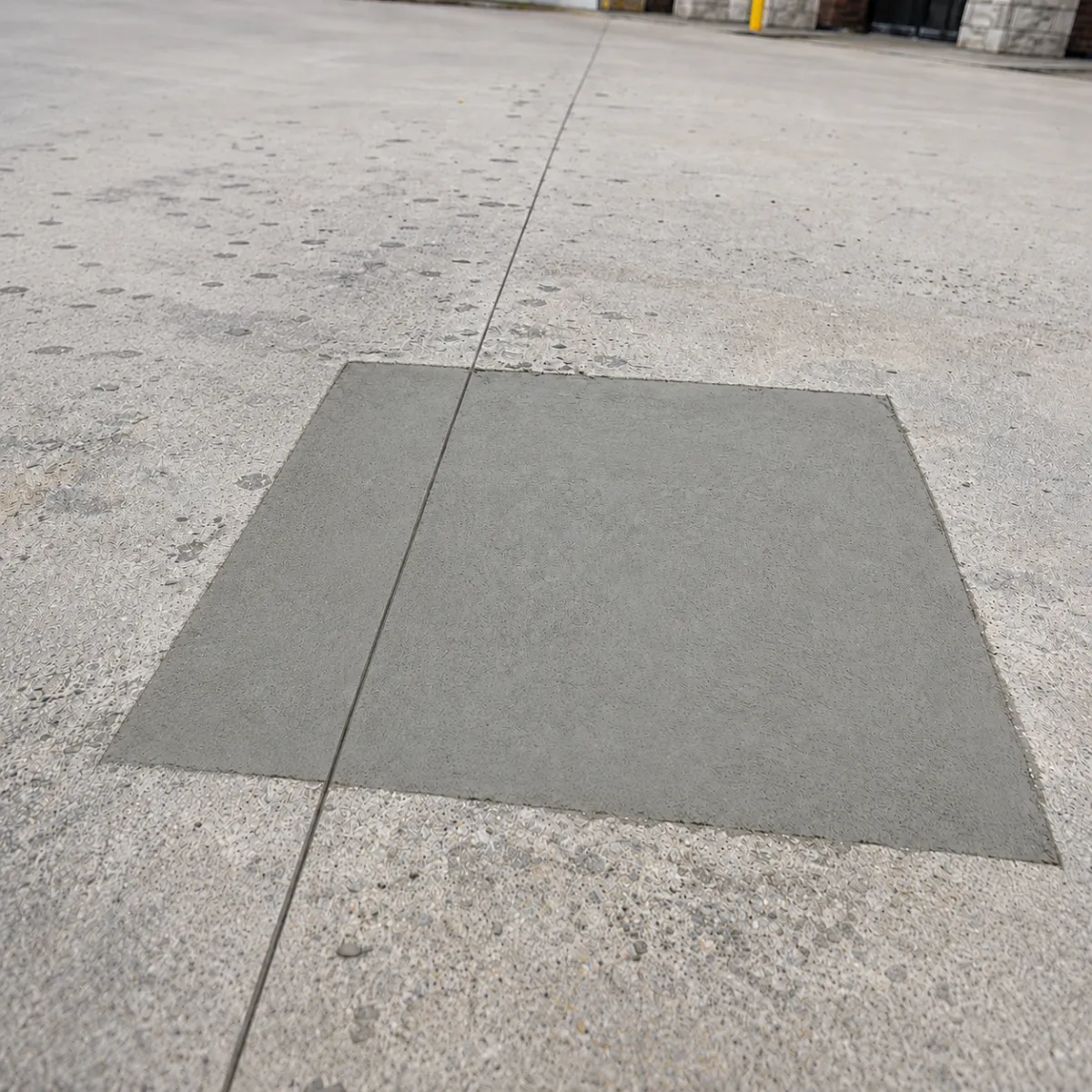 Fresh rectangular concrete patch repair installed within an existing commercial concrete pavement surface.