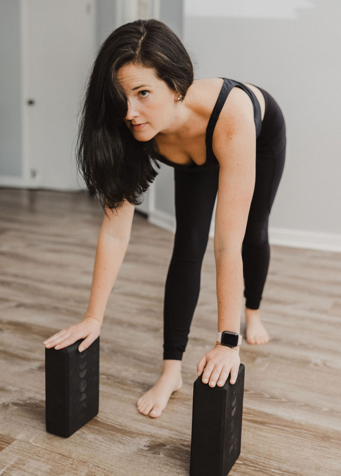 woman in white tank top and gray leggings lying on gray yoga mat