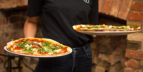 Brand photography for a Bedfordshire pub waitress in black holding two pizza