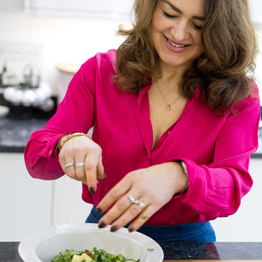 Personal branding photography of a nutritionist in a pink top making food