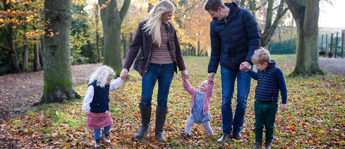 family portrait photography taken in the woods during autumn . wearing jeans and boots and winter coat.