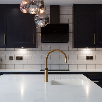 dark blue cupboard and white worktops with gold taps of a kitchen for brand photography