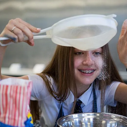 schools photography of a girl with braces looking at flour dropping through a sieve .