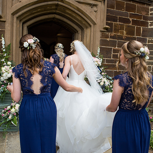 wedding photography of the back of a brides dress and her bridesmaids in blue