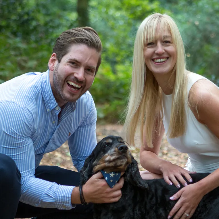 engaged couple  looking at the camera with their dog 