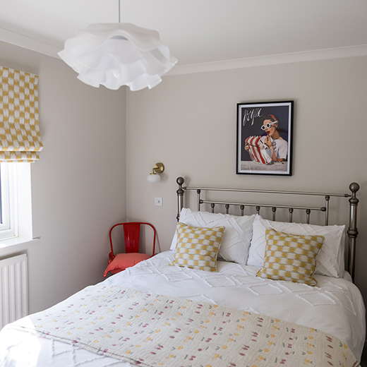 Interior photography of white bedroom with red and yellow detail on the cushion and blinds