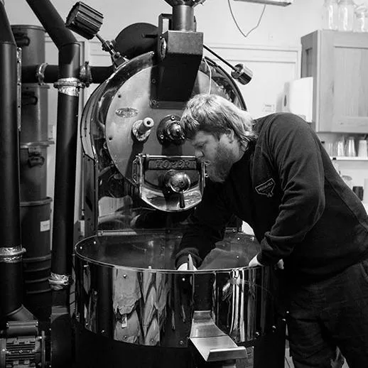 portrait photography of a coffee roster in front of his machine demonstrating his skills at Woodenhill in Bedfordshire
