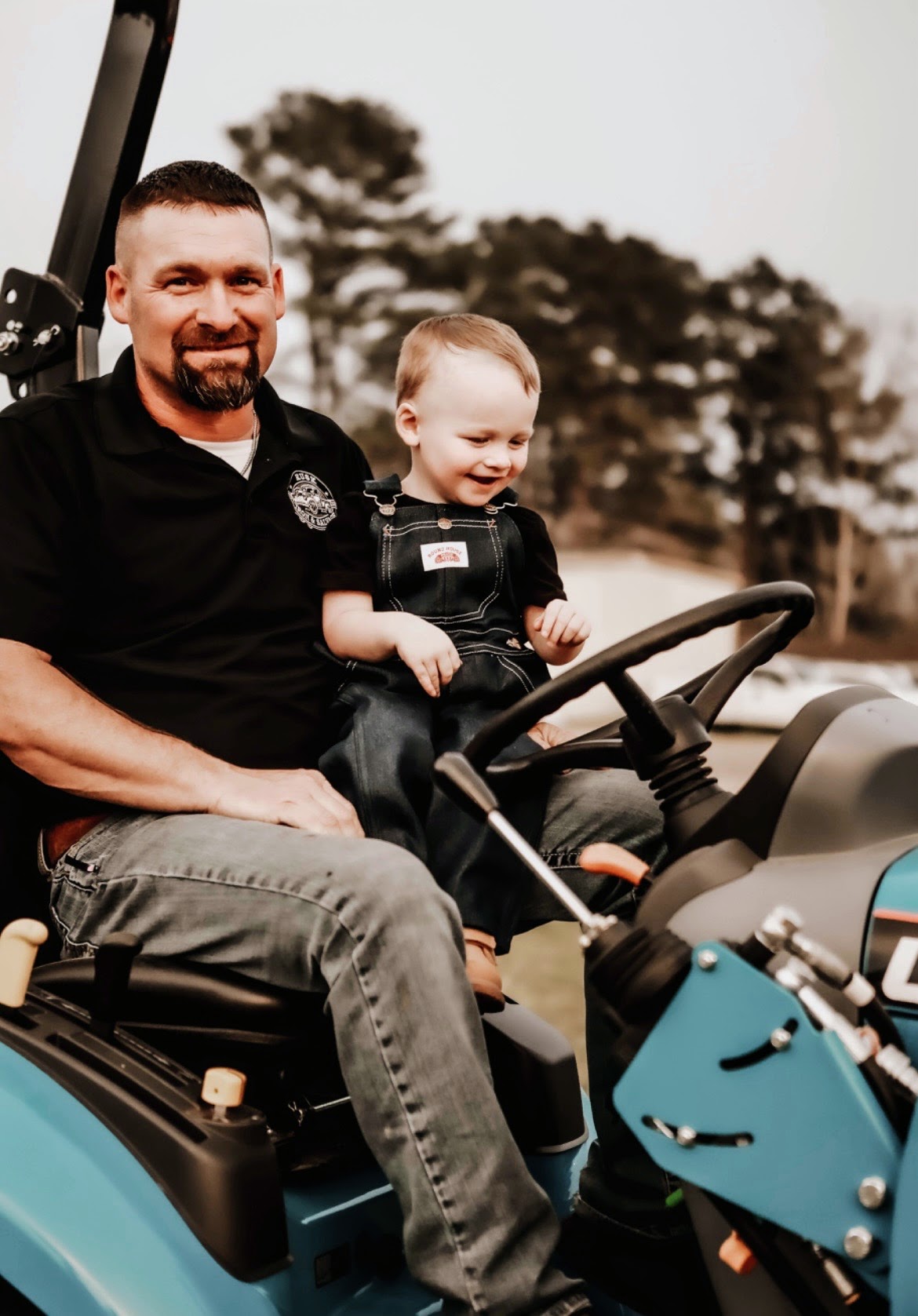 Brandon Hudnall with his Grandbaby on the tractor.