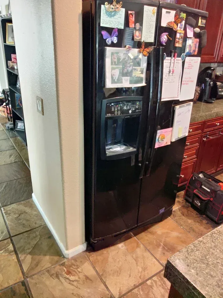 A certified appliance technician testing a kitchen refrigerator unit with a digital meter in Selma, CA near the Highway 99 commercial corridor.