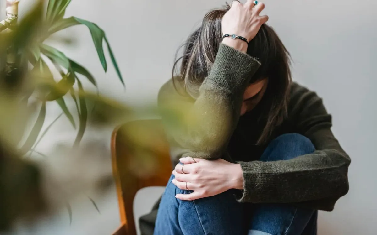Woman sitting with head down hand on head looking sad