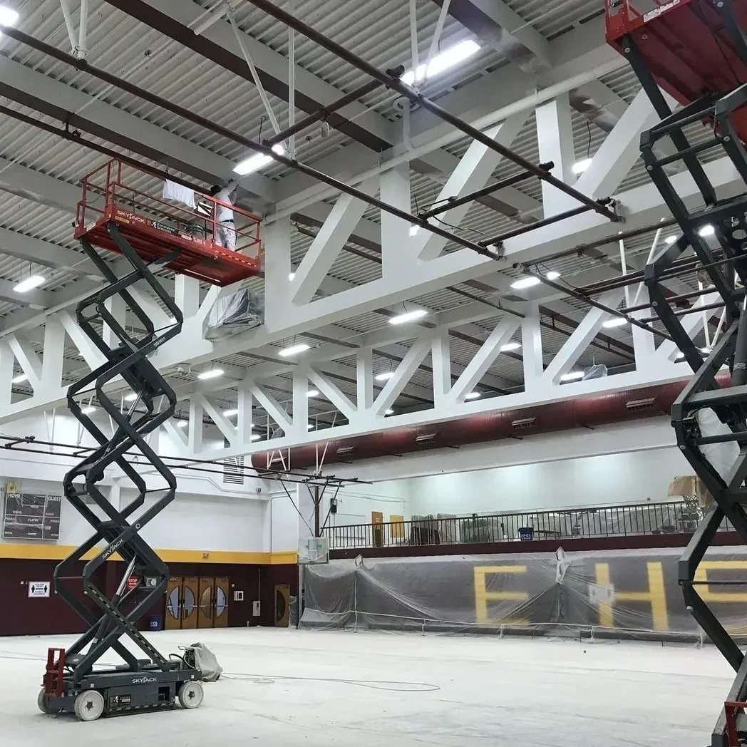 AllPro crew repainting a school gymnasium in Las Vegas with the floor cleared and the bleachers masked off