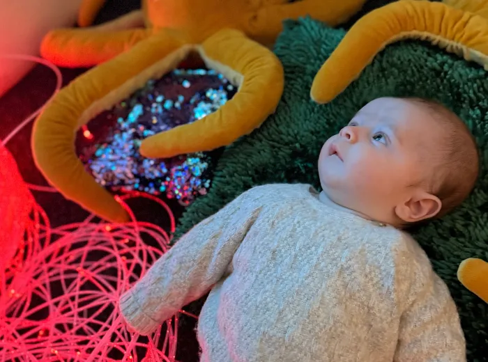 Infant exploring sensory play with colorful lights and textures at Curious Minds Early Years Academy, Horizon West