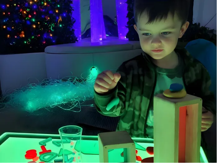 Preschool-aged child experimenting with light and colorful learning materials at Curious Minds Early Years Academy, Horizon West