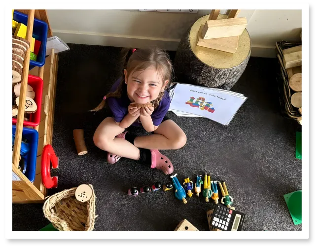 Young child engaged in creative play with wooden building blocks and colorful learning materials at Curious Minds Early Years Academy, Horizon West