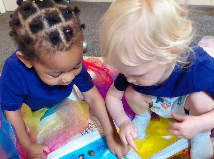Toddlers engaged in creative play with rainbow-colored materials at Curious Minds Early Years Academy, Horizon West