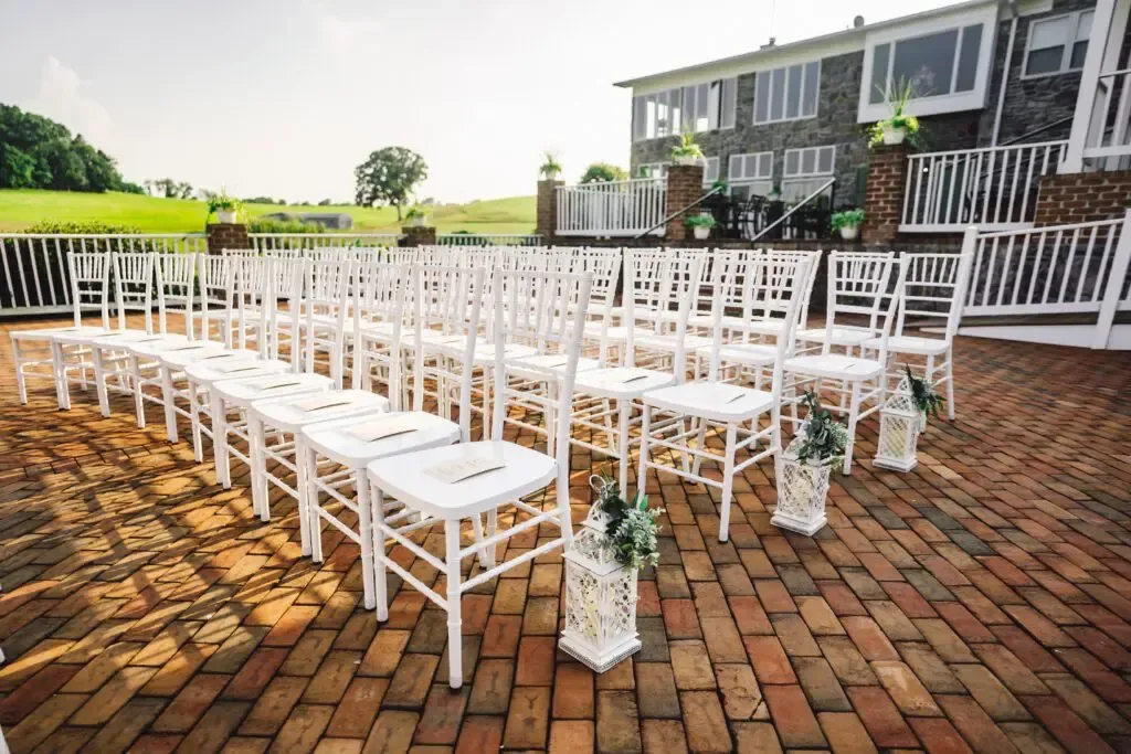 Outdoor wedding ceremony setup at Morningside Inn with white chairs, floral lantern aisle decor, and a brick patio overlooking scenic farmland