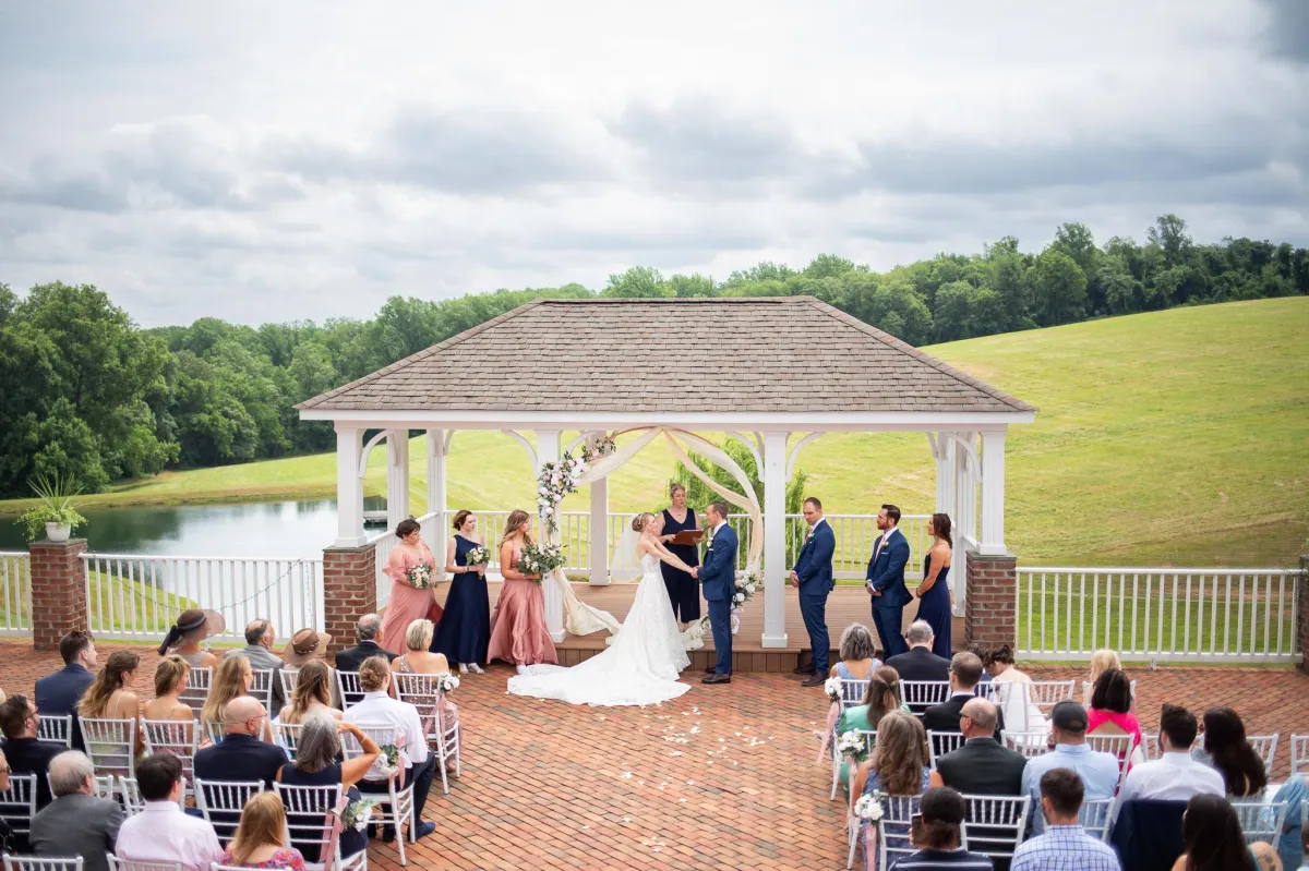 Wedding ceremony in progress at Morningside Inn, with the couple exchanging vows under a decorated gazebo overlooking rolling hills and a pond