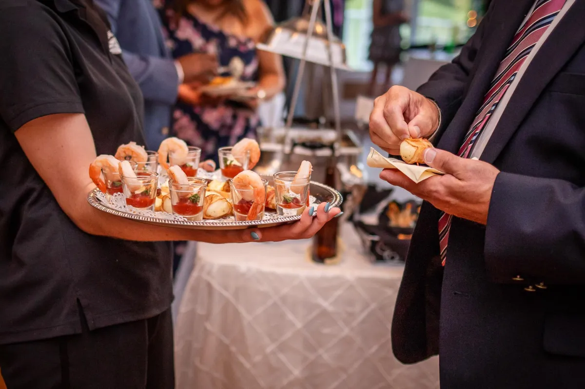 Server offering shrimp cocktail and hors d'oeuvres on a silver tray during a wedding reception at Morningside Inn