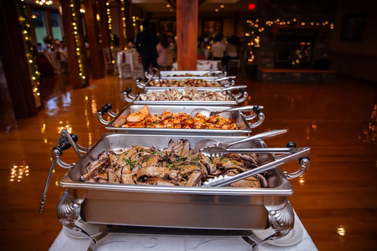 Server presenting a silver tray of gourmet hors d'oeuvres at Morningside Inn, with a red rose garnish and green lawn in the background