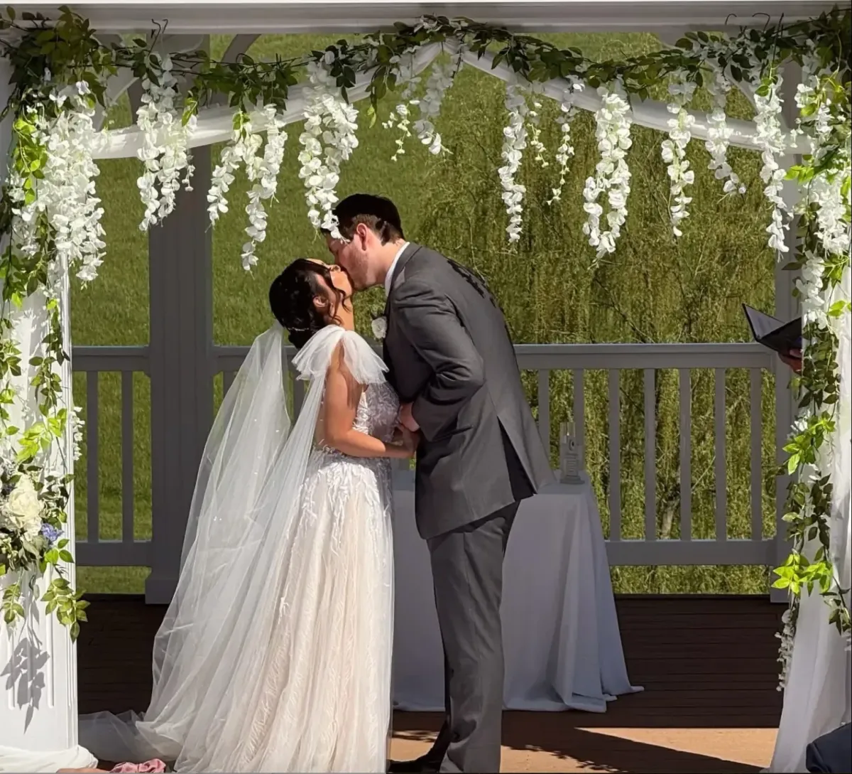 Bride and groom sharing a kiss on the hilltop at Morningside Inn, with a scenic pond, rolling hills, and lush trees in the background