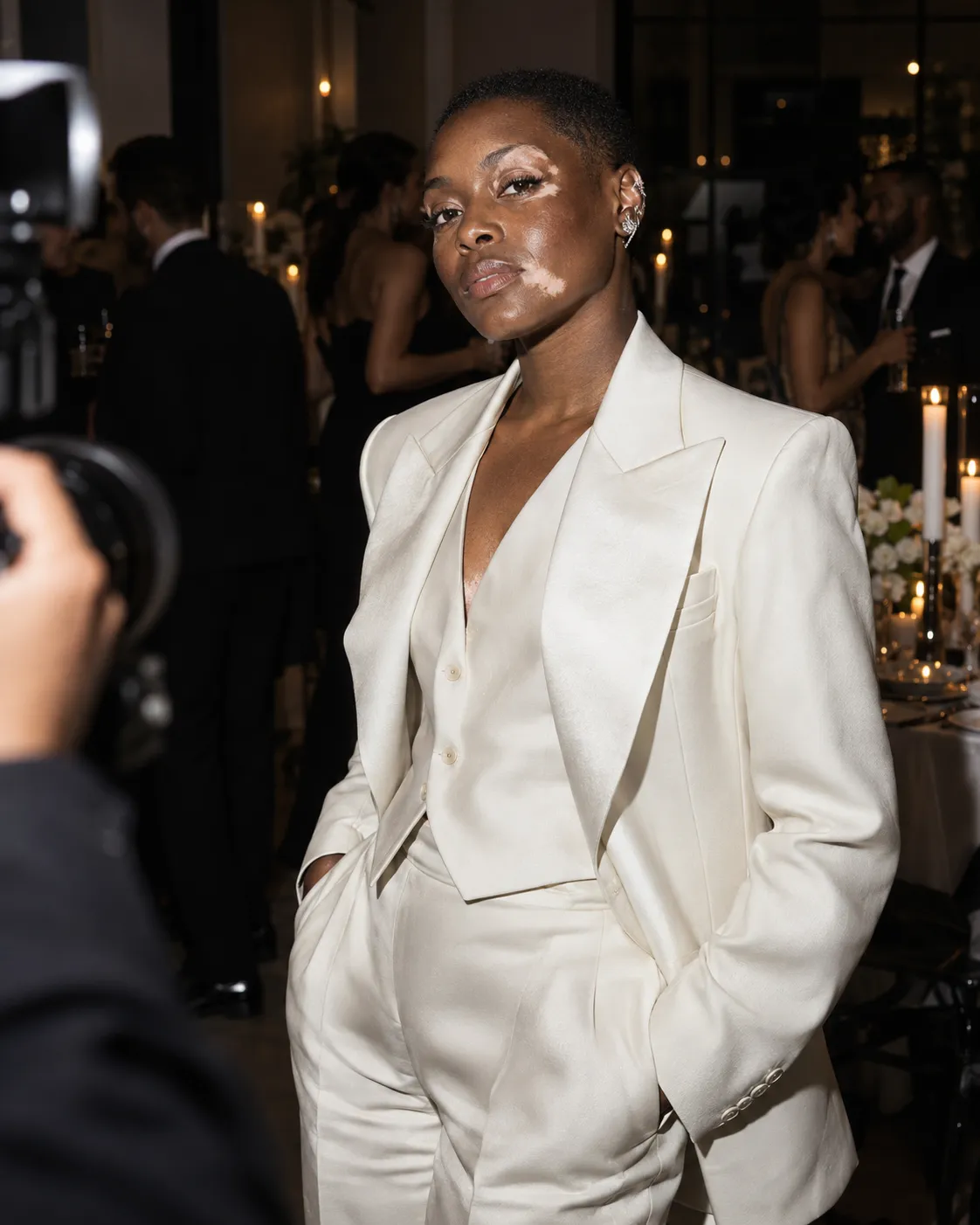 Black bride with vitiligo wearing an ivory suit during an evening direct-flash portrait.