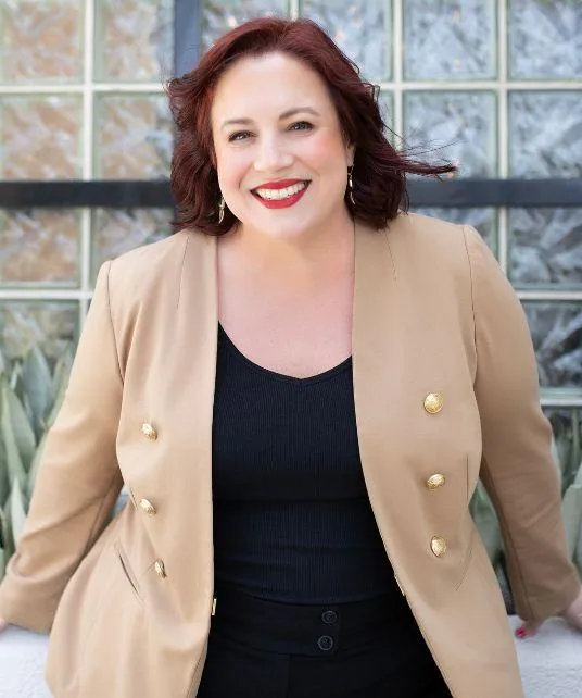 Brunette woman with red lipstick, beige jacket, and black shirt