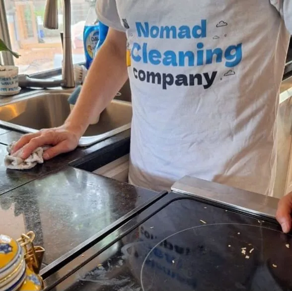 Nomad Cleaning team member wiping kitchen counters in a home