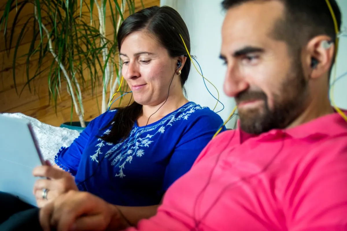 A couple enjoying a NeurOptimal® neurofeedback brain training session together while they relax on a couch.