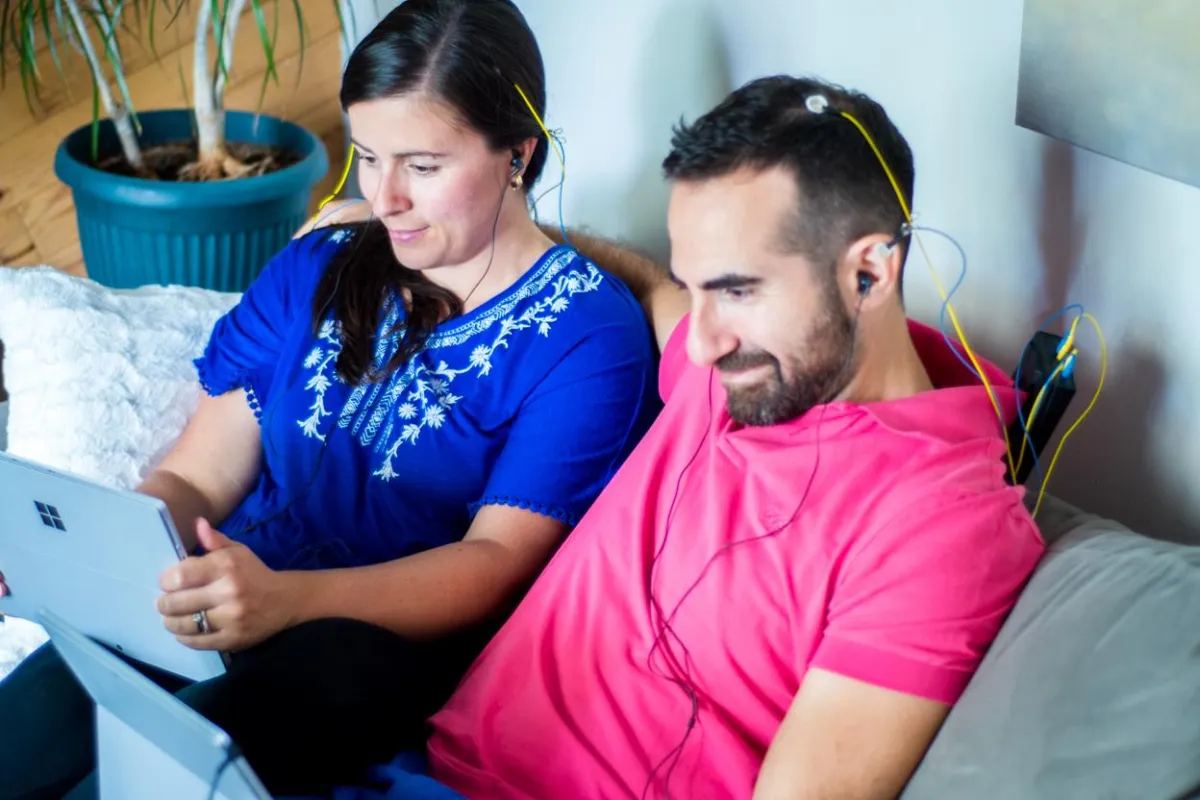 a man and his wife on a couch engaged in at home neurofeedback brain training