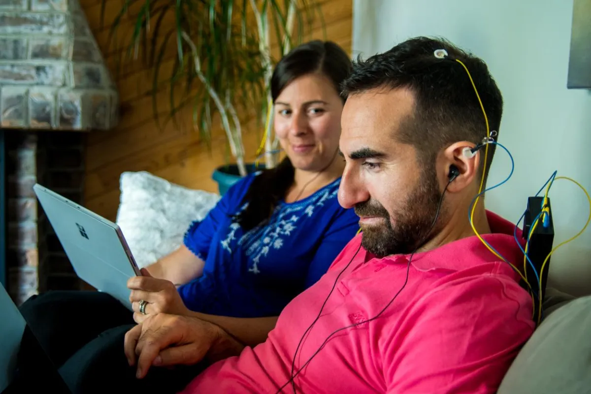 A couple enjoying a NeurOptimal® neurofeedback brain training session together while they relax on a couch.