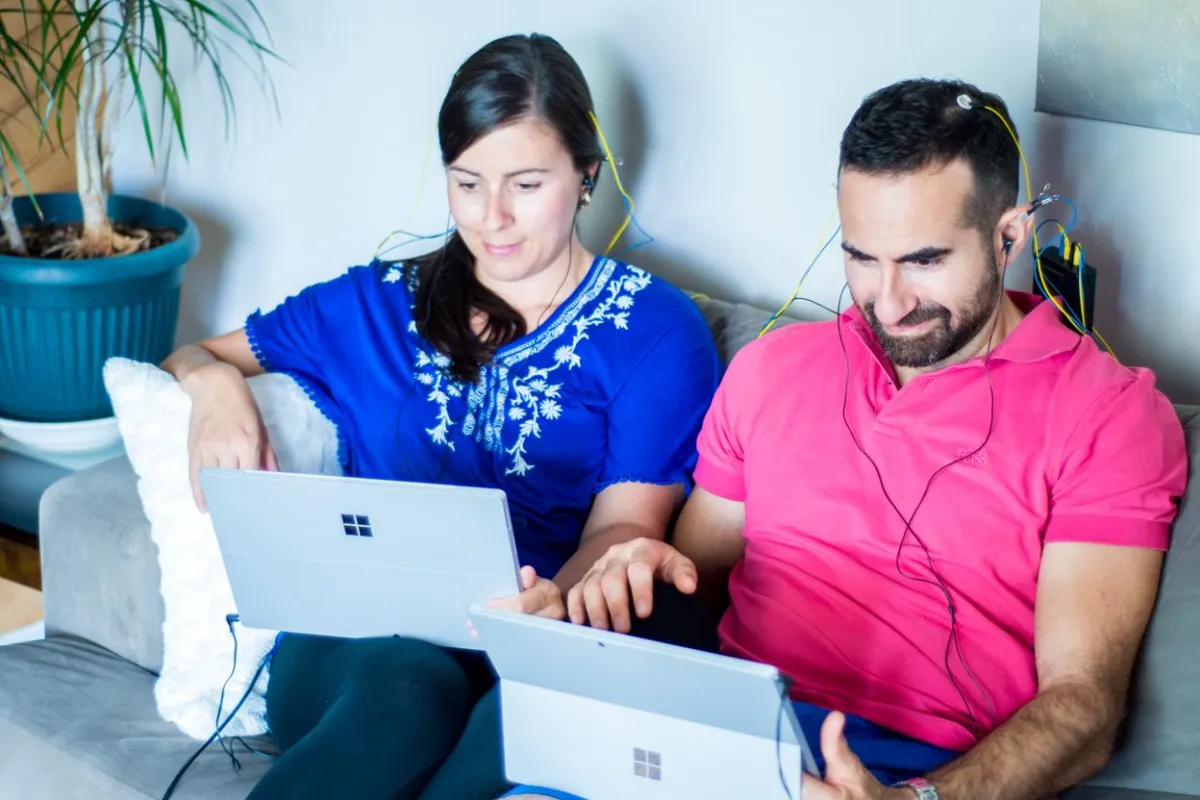 A couple enjoying a NeurOptimal® neurofeedback brain training session together while they relax on a couch.