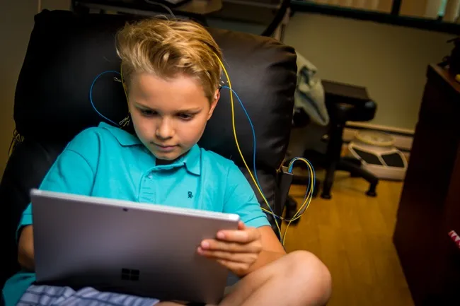 a boy engaging in a neurofeedback session in recliner chair