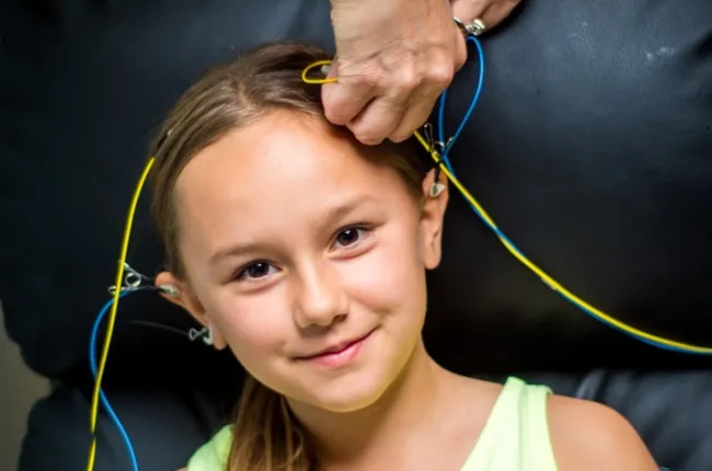 girl happily getting ready for a neurofeedback session