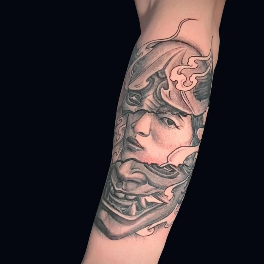 a black and gray tattoo of a Japanese mask refilling a girl's face on the outer form done in Oceanside, California