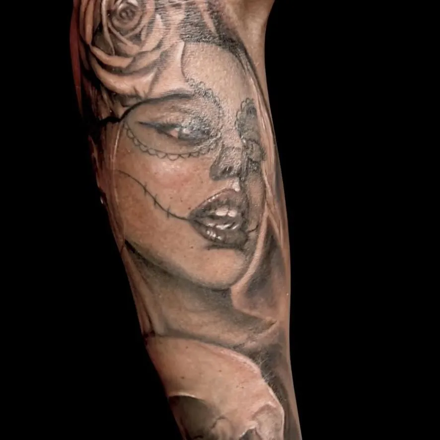 a tattoo, black and gray of a girl resembling the day of the dead on the forearm in Oceanside, California