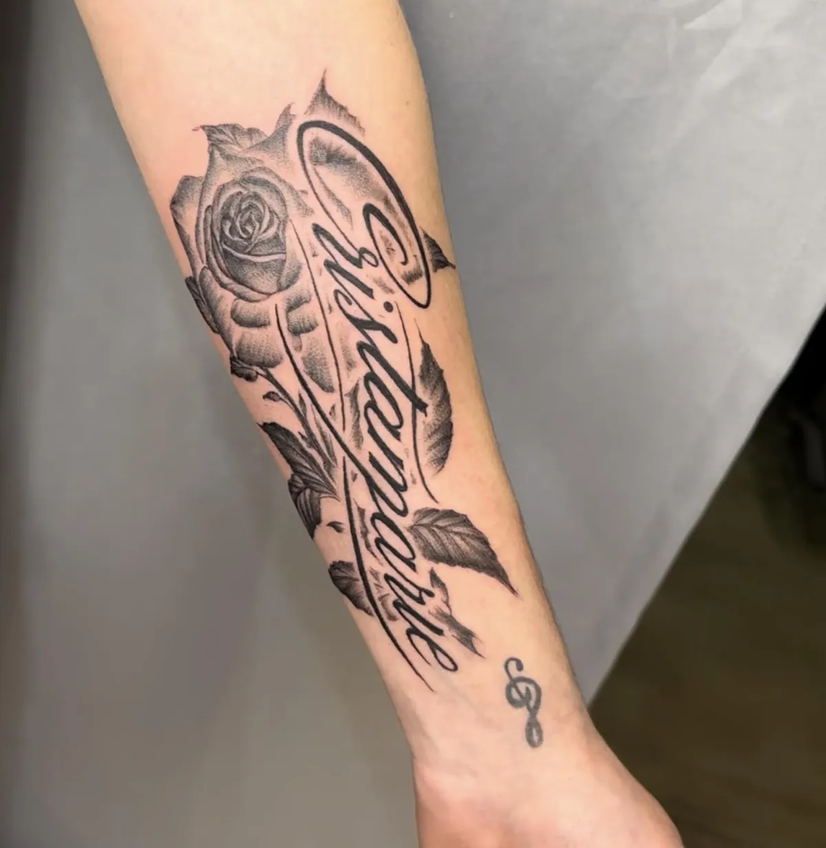 Black work tattoo of a rose with lettering done on the forearm in Oceanside, California